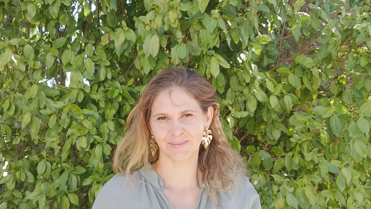 Charlotte Pons, sophrologue à Prades-le-Lez, en extérieur devant un feuillage